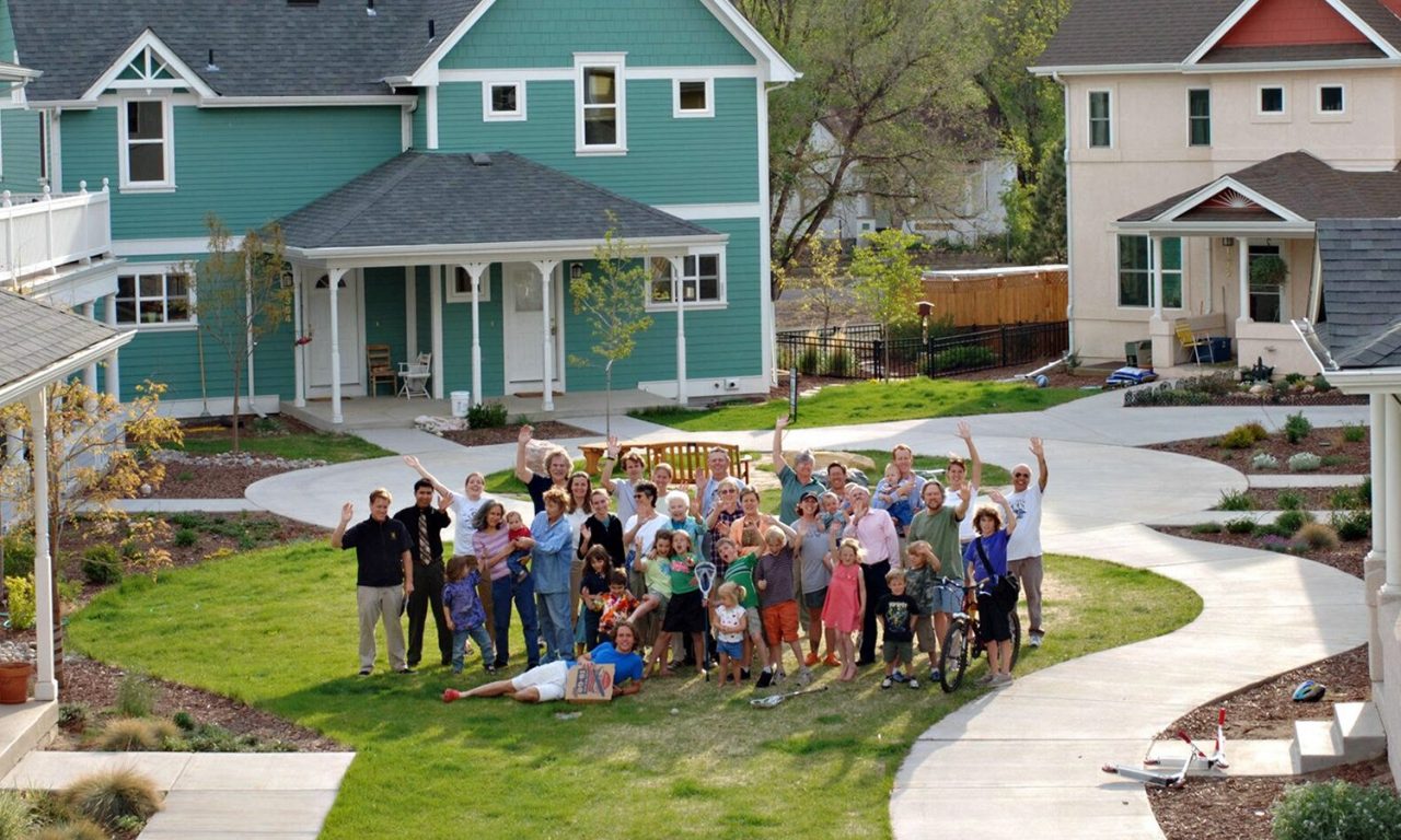 Foto grupal de familias en el centro de una plaza en una comunidad de cohousing