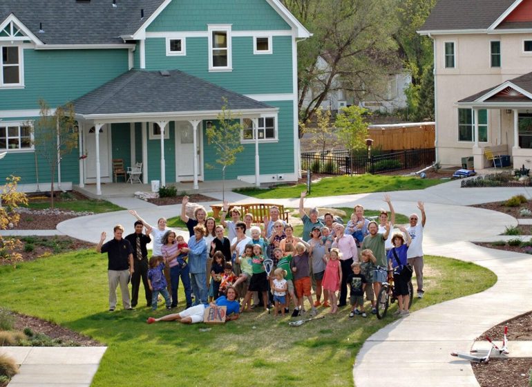 Foto grupal de familias en el centro de una plaza en una comunidad de cohousing